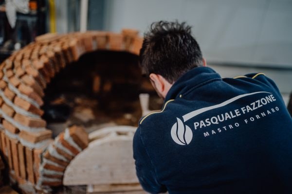 Kemenceépítő Pasquale Fazzone feliratú pulóverben a félkész kupola előtt