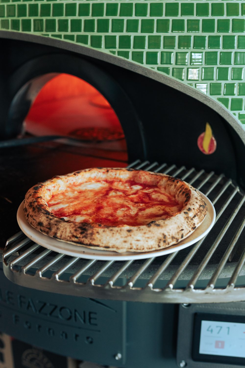 Frissen sült nápolyi pizza a zöld mozaikos Leaf Oven kemence peremén