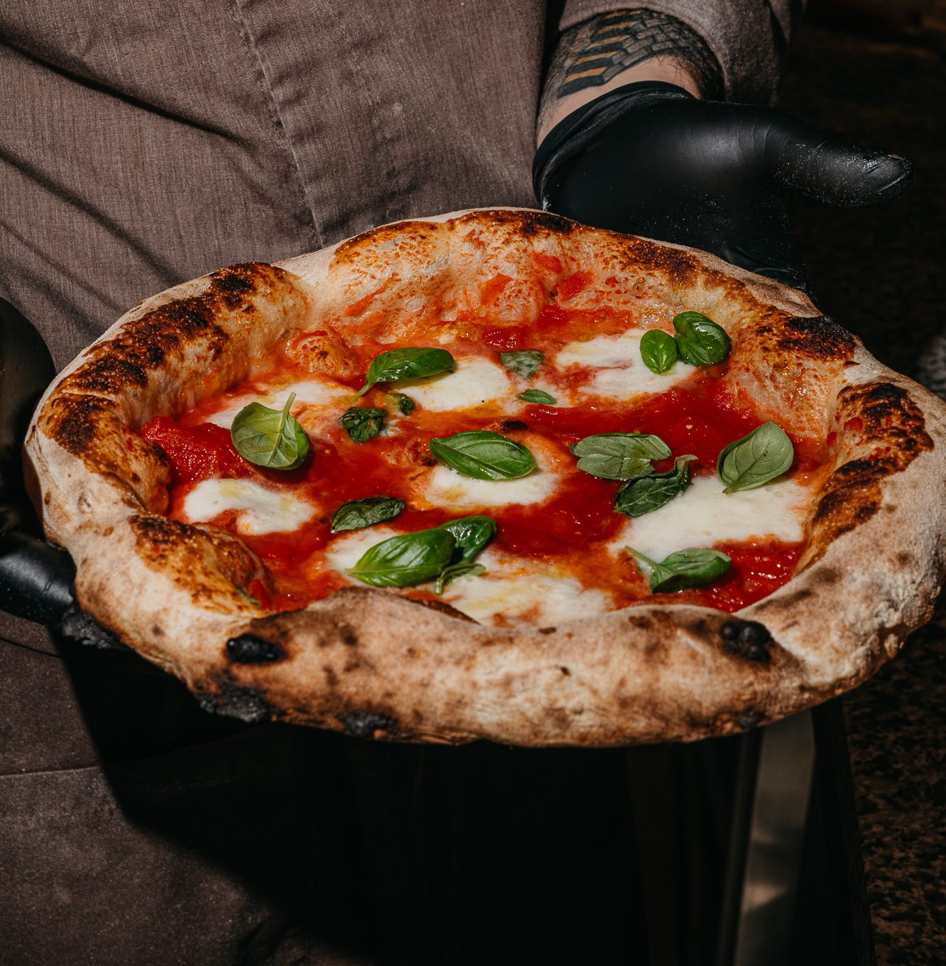 Frissen sült nápolyi margherita pizza egy pizzaiolo kezében